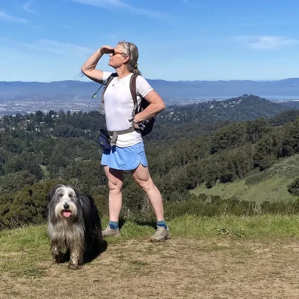Rebecca Lewington and her dog looking out over the East Bay from a ridge trail