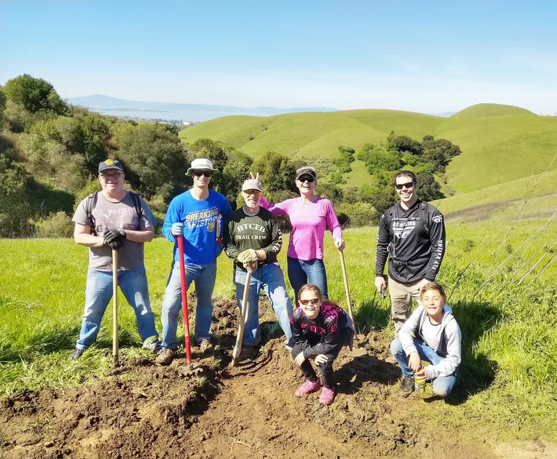 A volunteer trail crew on a green East Bay hillside
