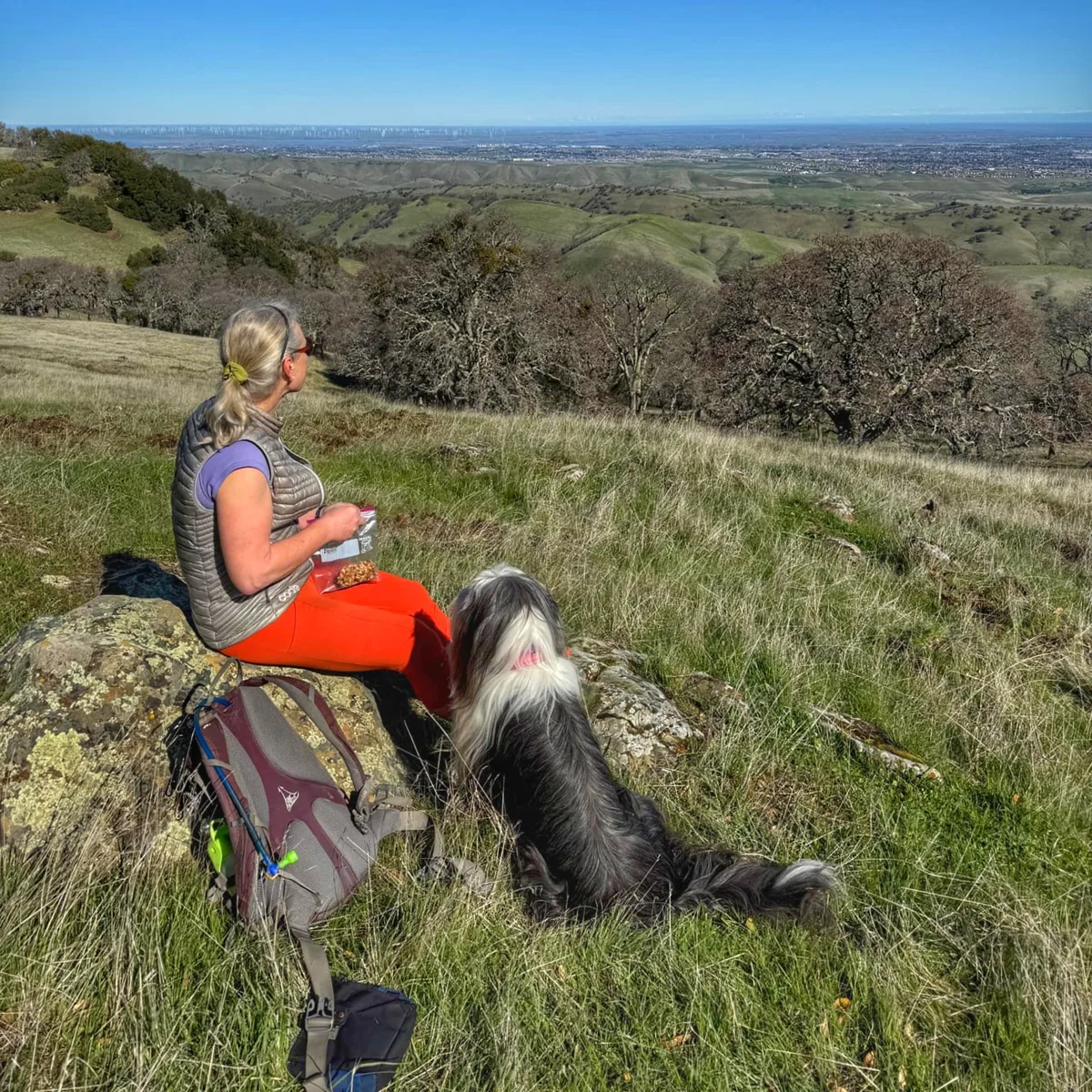 Rebecca Lewington resting with her dog above an East Bay valley